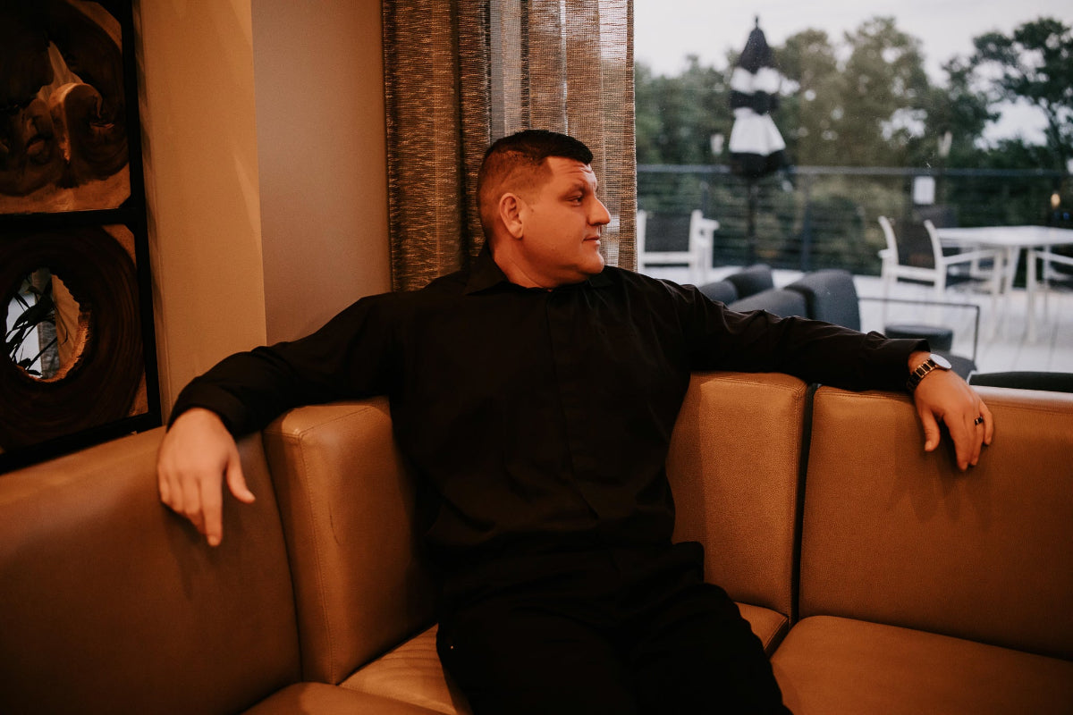 Nick Vonella sitting on a brown leather couch in a room with decorative elements.